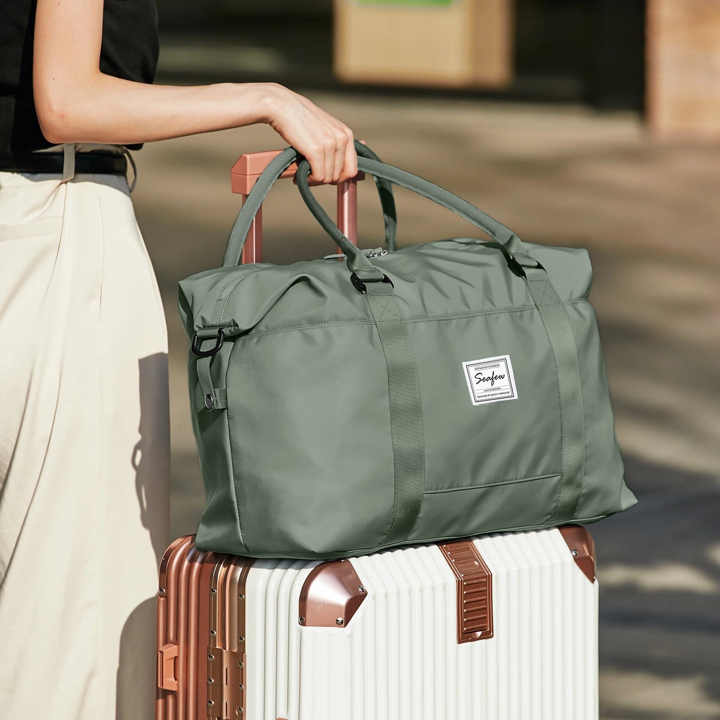 Sac de voyage pliable vert olive pour week-end, posé sur valise blanche, idéal pour voyages et déplacements