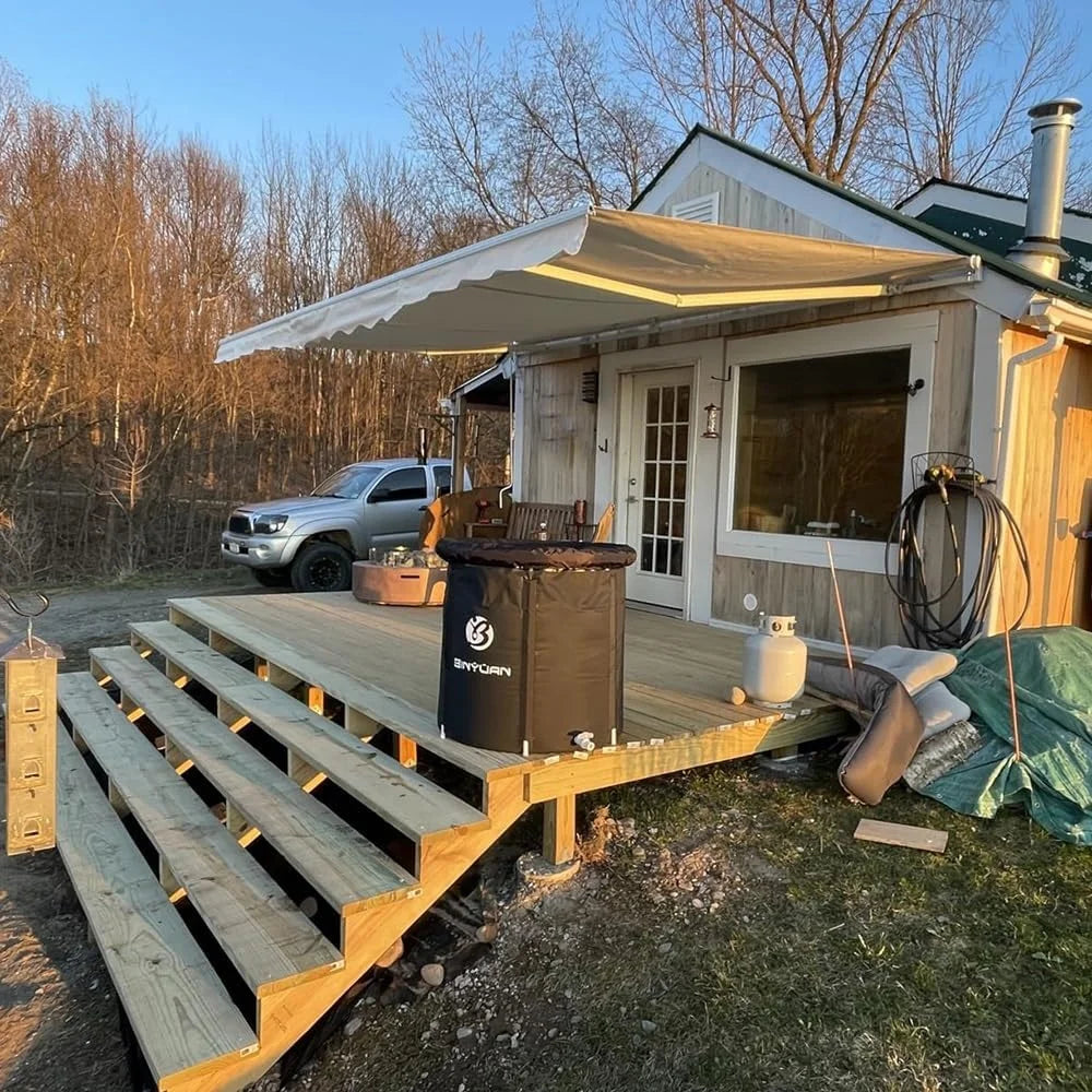Terrasse en bois avec auvent, poêle à gaz et camion en arrière-plan, idéal pour camping ou tiny house