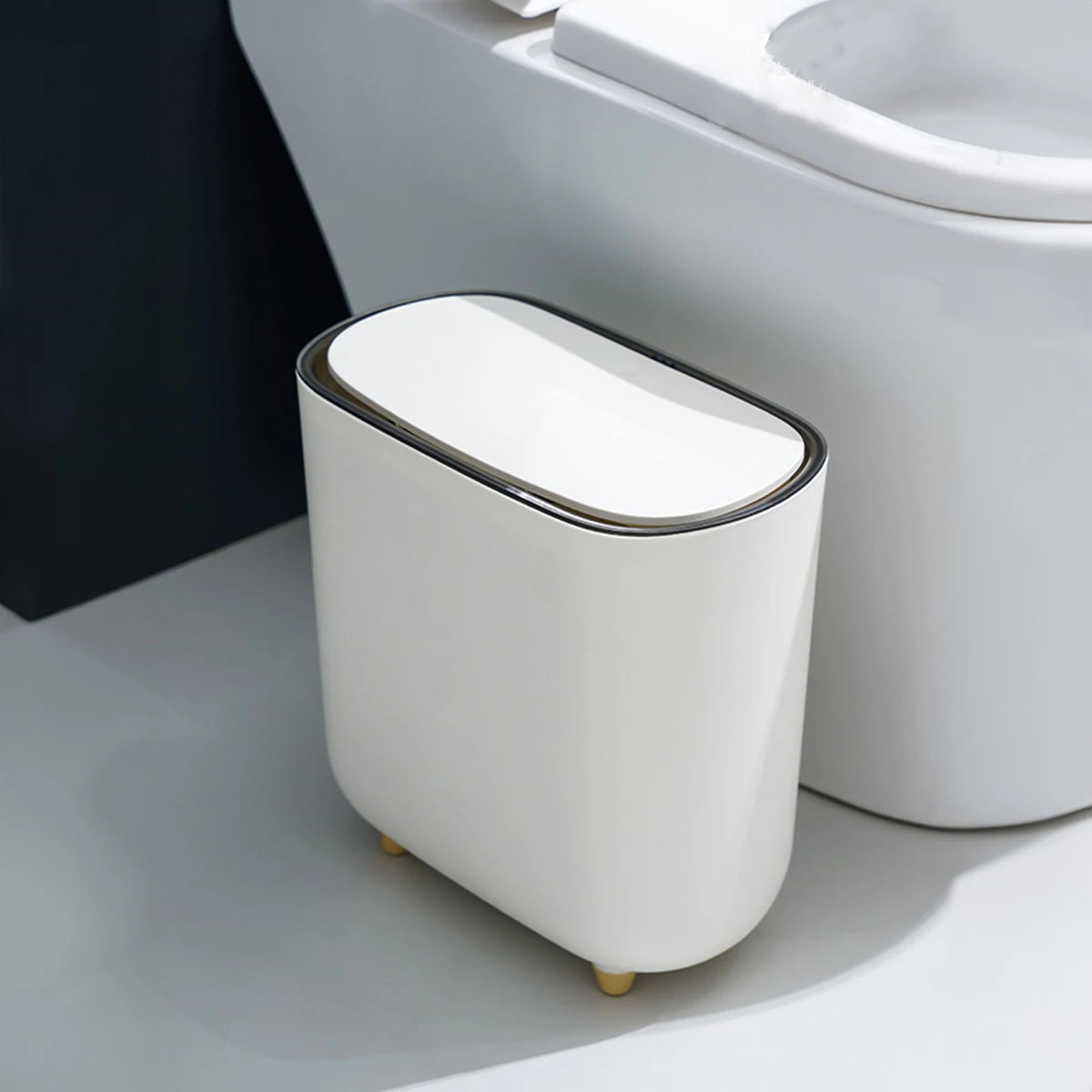 Poubelle de salle de bain blanche moderne avec couvercle et pieds dorés, design compact et élégant