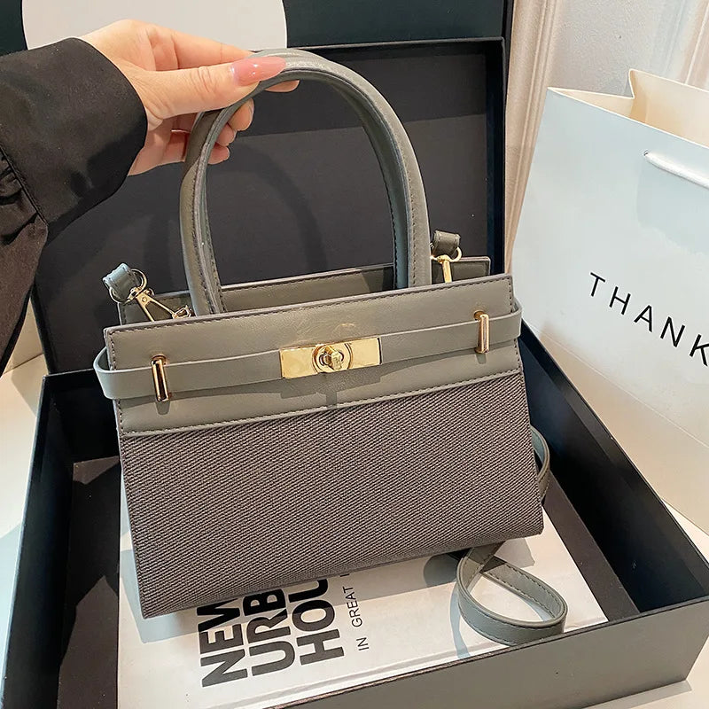 Sac à main gris élégant avec fermeture dorée, idéal pour un style urbain chic