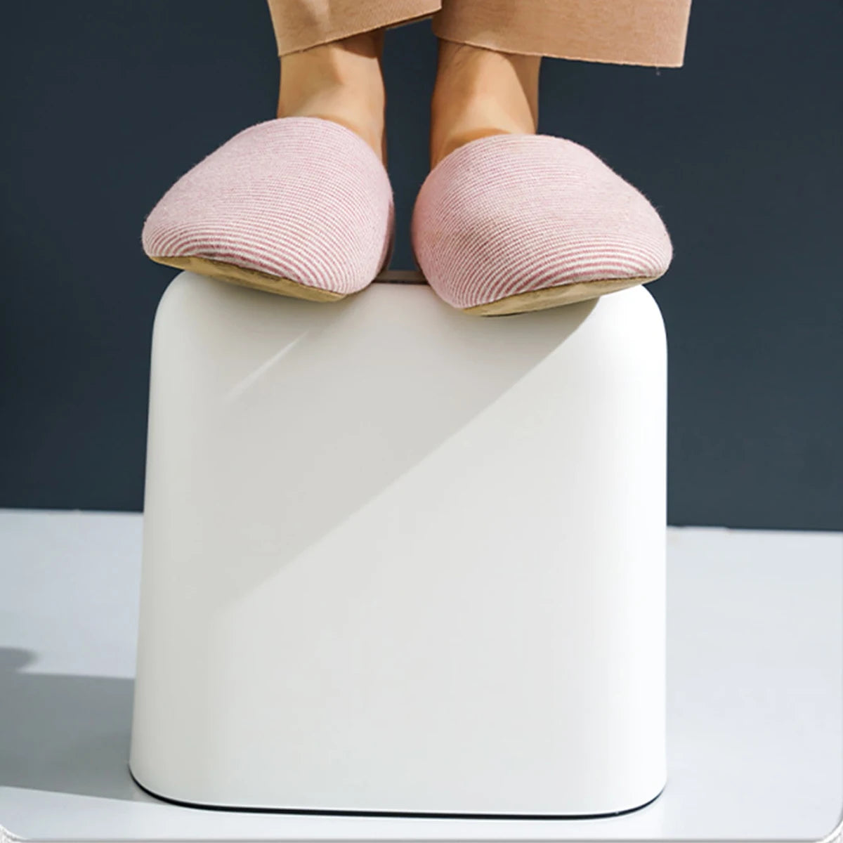 Pieds en chaussons roses sur repose-pieds blanc design ergonomique