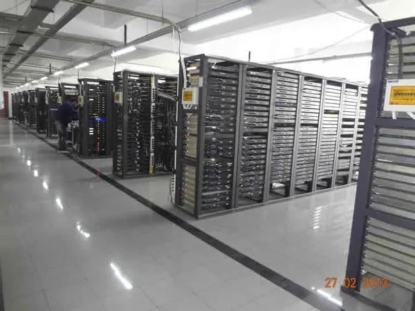 Salle des serveurs avec rangées de racks informatiques et technicien en maintenance