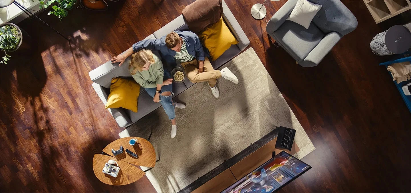 Couple détendu sur canapé avec télévision et gadgets high-tech dans salon moderne
