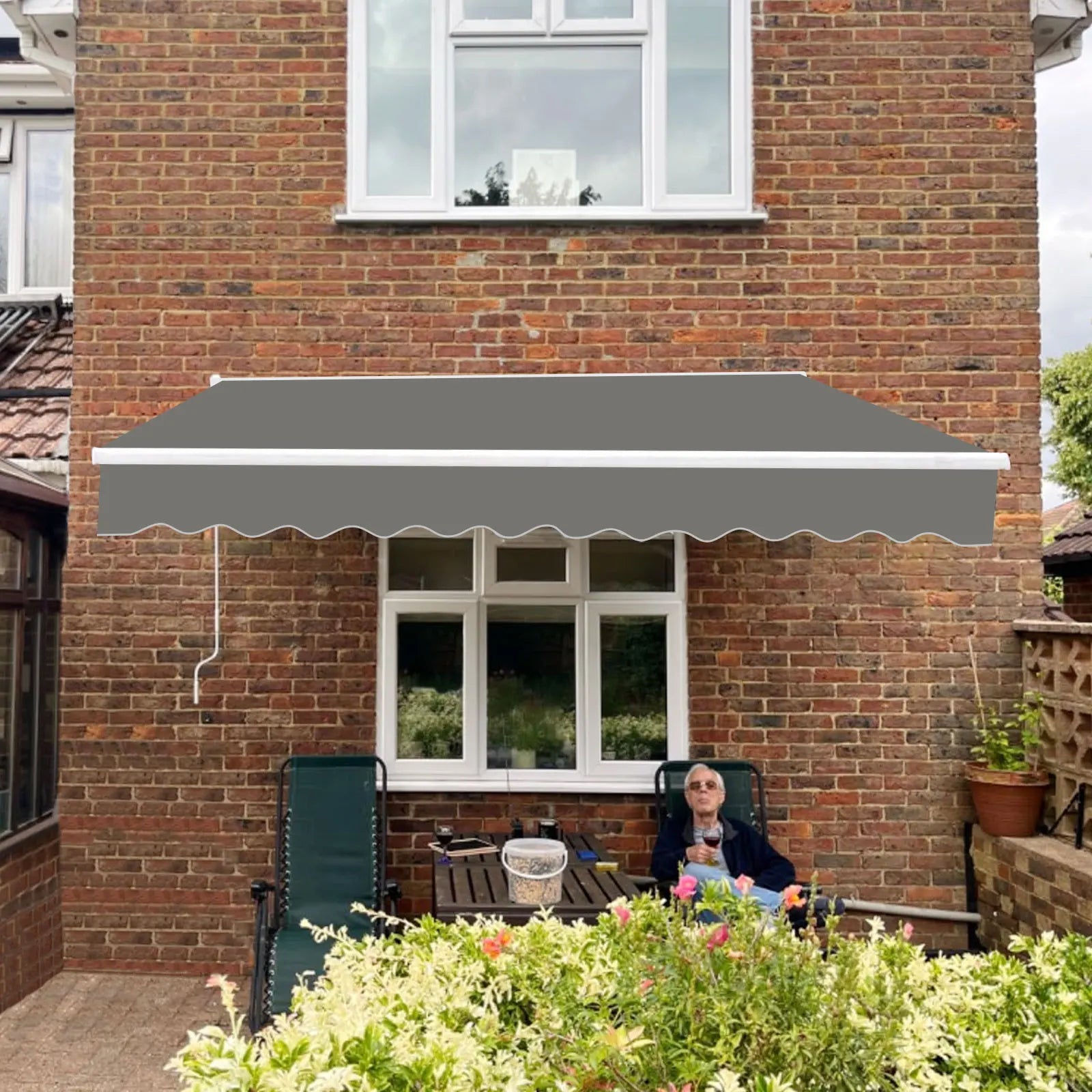 Auvent de terrasse gris avec bordure ondulée, installé sur mur en briques, pour ombrage extérieur et confort jardin