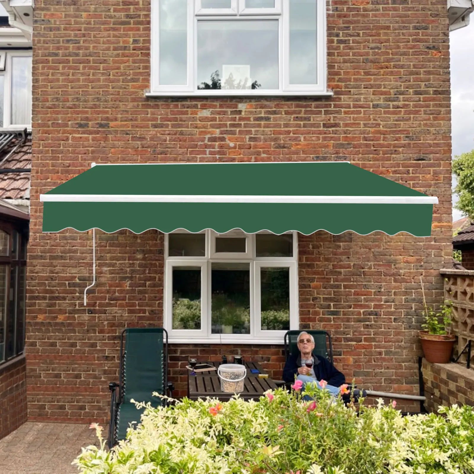 Auvent de terrasse vert foncé pour extérieur, protection solaire sur patio avec fauteuils et jardin fleuri