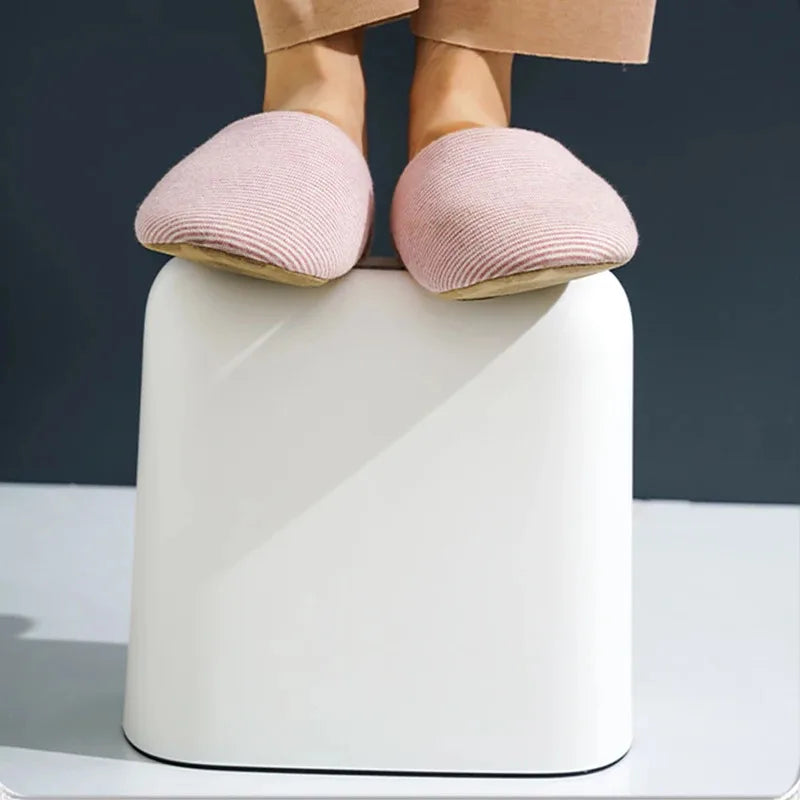 Pieds en chaussons roses sur repose-pieds blanc ergonomique